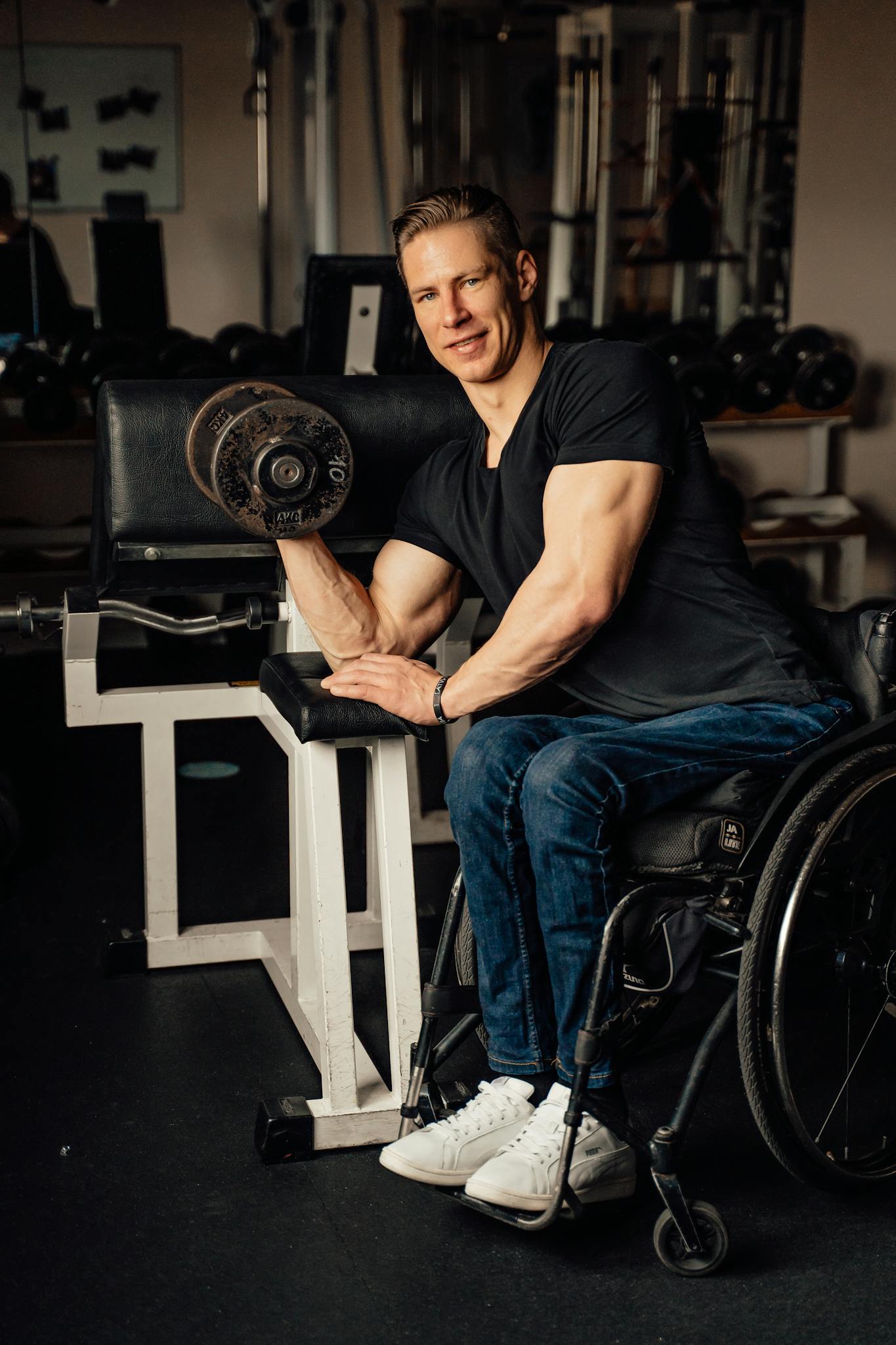 Man in a wheelchair lifting dumbbell in gym showing strength and determination.